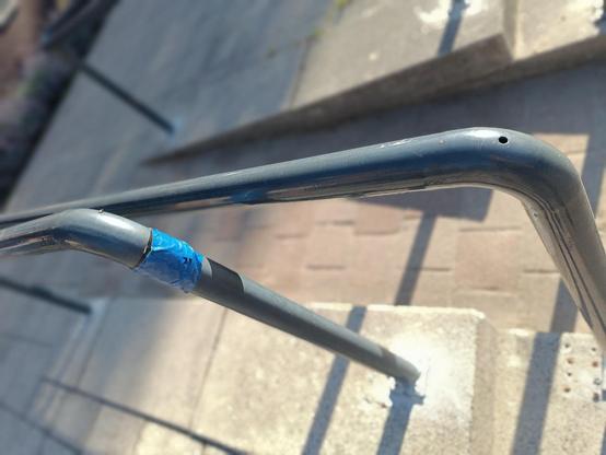A photo with confusing perspective showing a metal railing wrapped in thick blue duct tape near one of the bands.